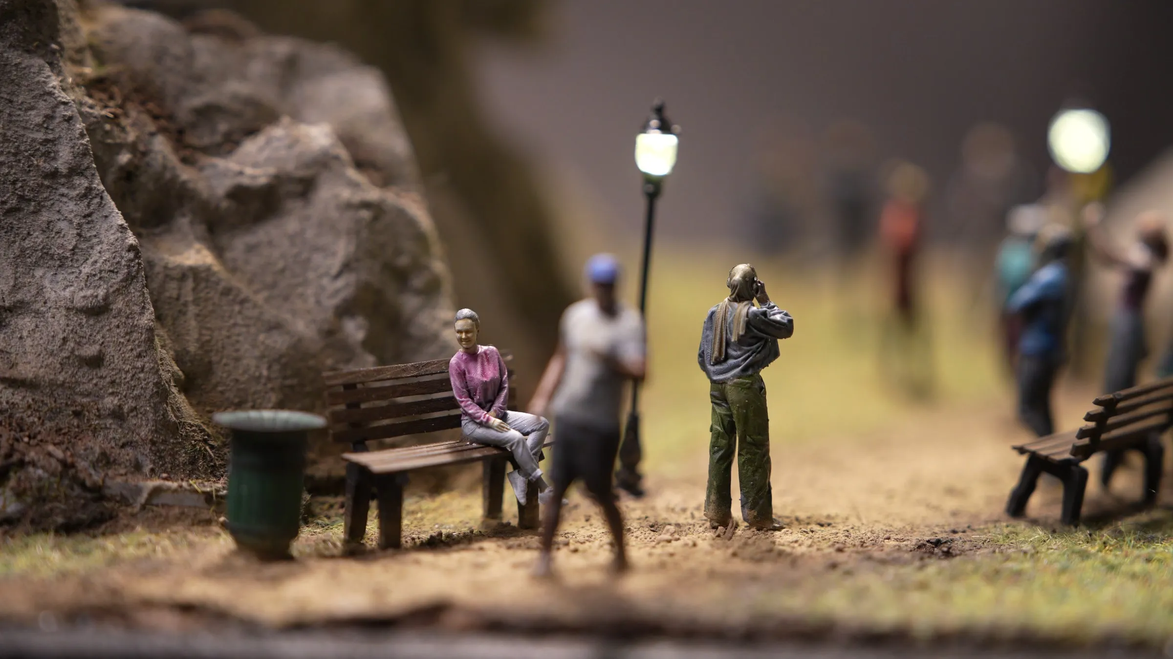 Hand-painted resin figures by a park bench, bin and street lamps