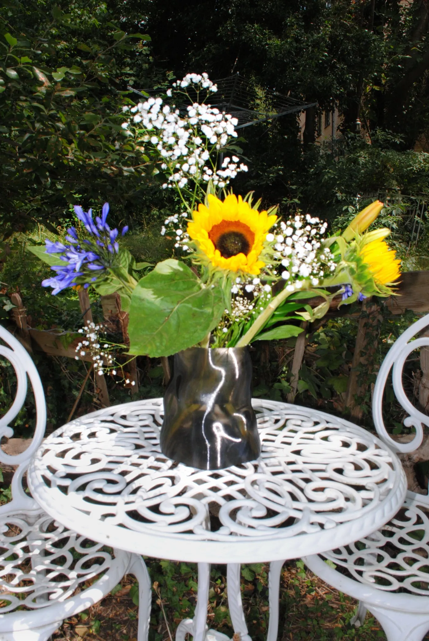 Peski vase in Gun Metal with sunflowers and agapanthus on a garden table