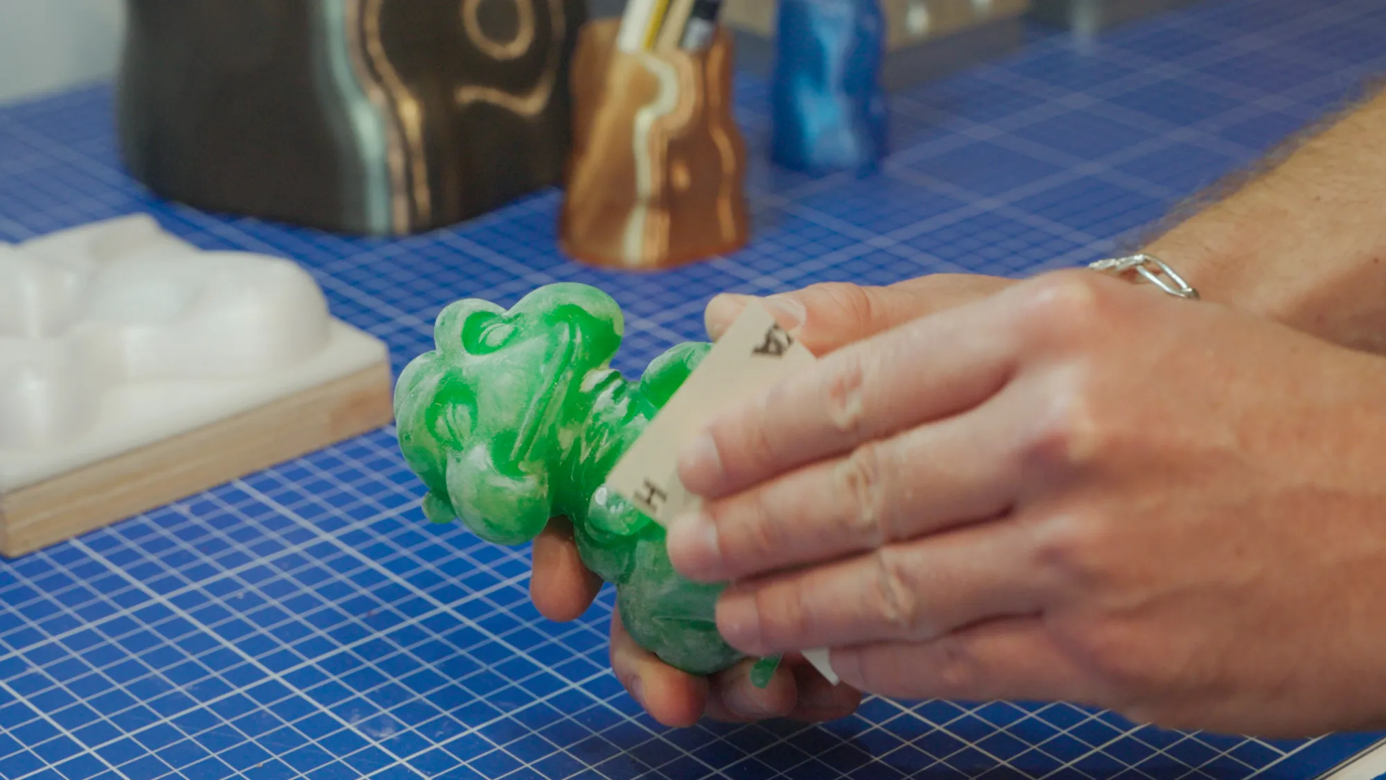 Hand-sanding a green resin figure at the Spike TM workbench